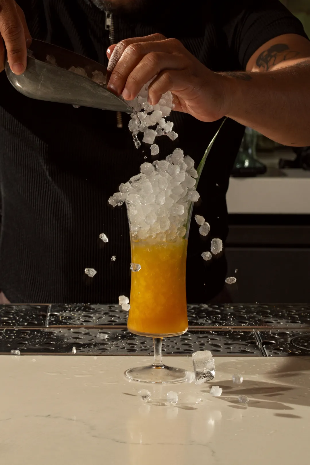 Crushed ice tumbling into a tall cocktail glass
