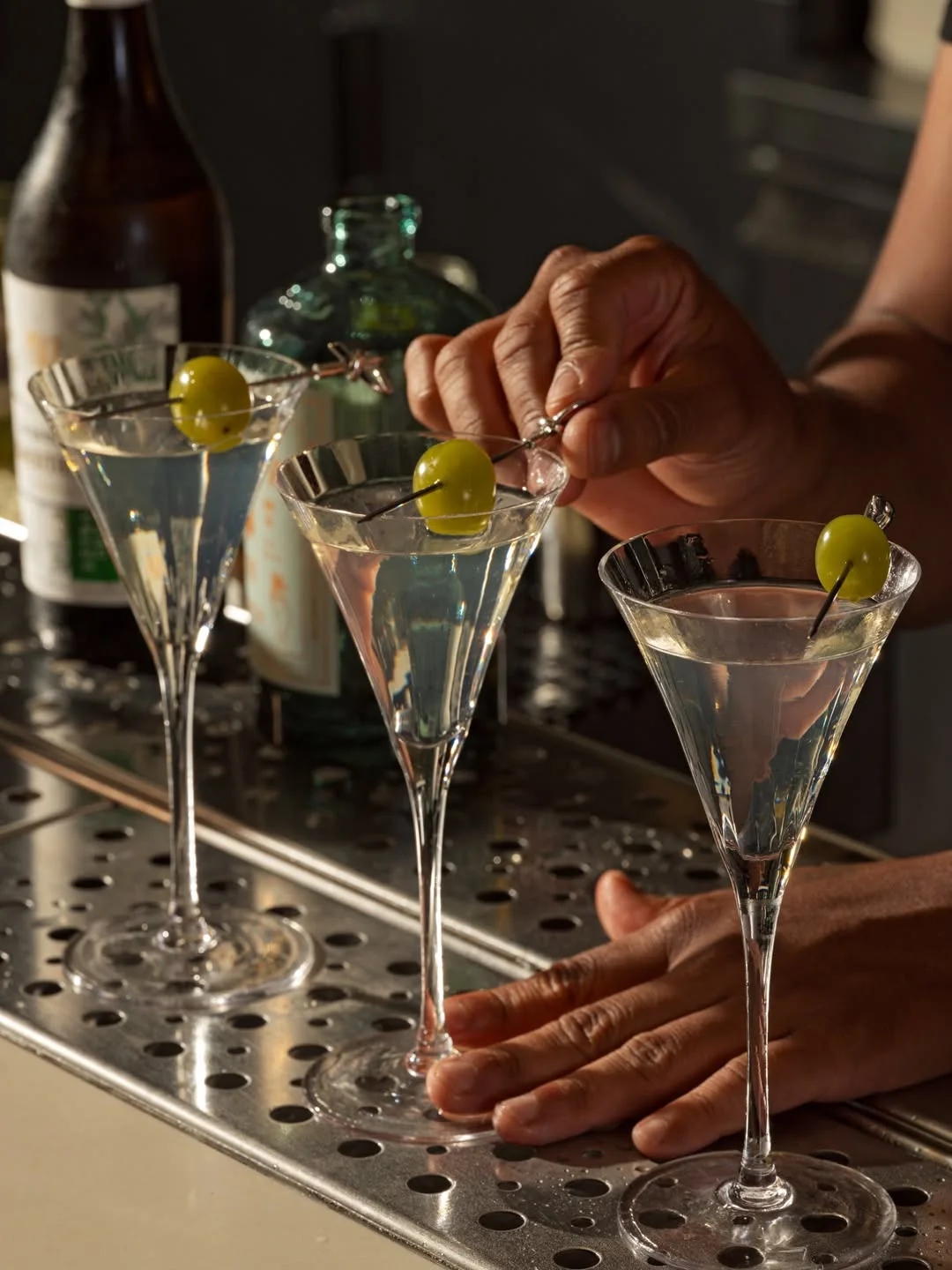 Pinning olives on three martinis behind the bar