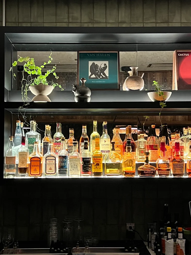 The back bar shelf, bottles glowing under a Van Halen record