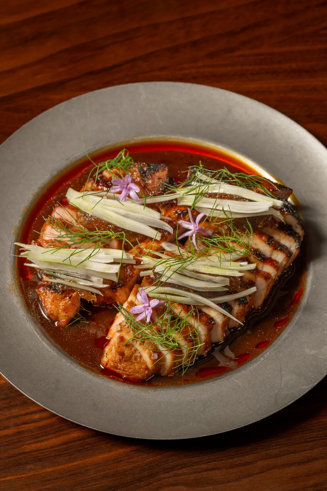 Barbecue pork chop in a red broth with shaved fennel