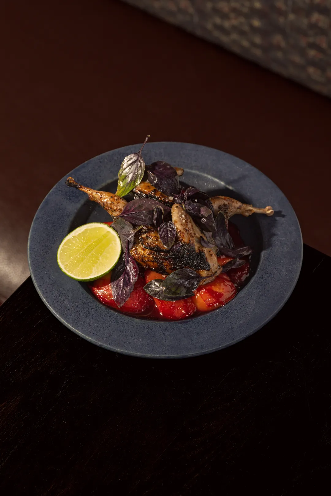 Grilled quail over tomatoes with purple basil and lime