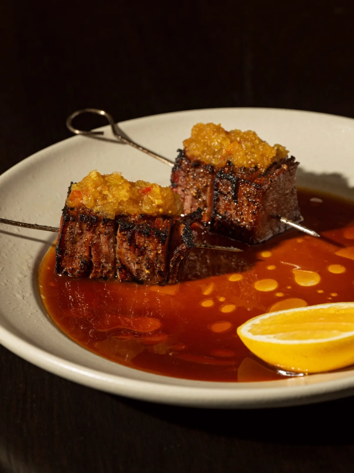 Charred beef skewers in a burnished sauce with lemon