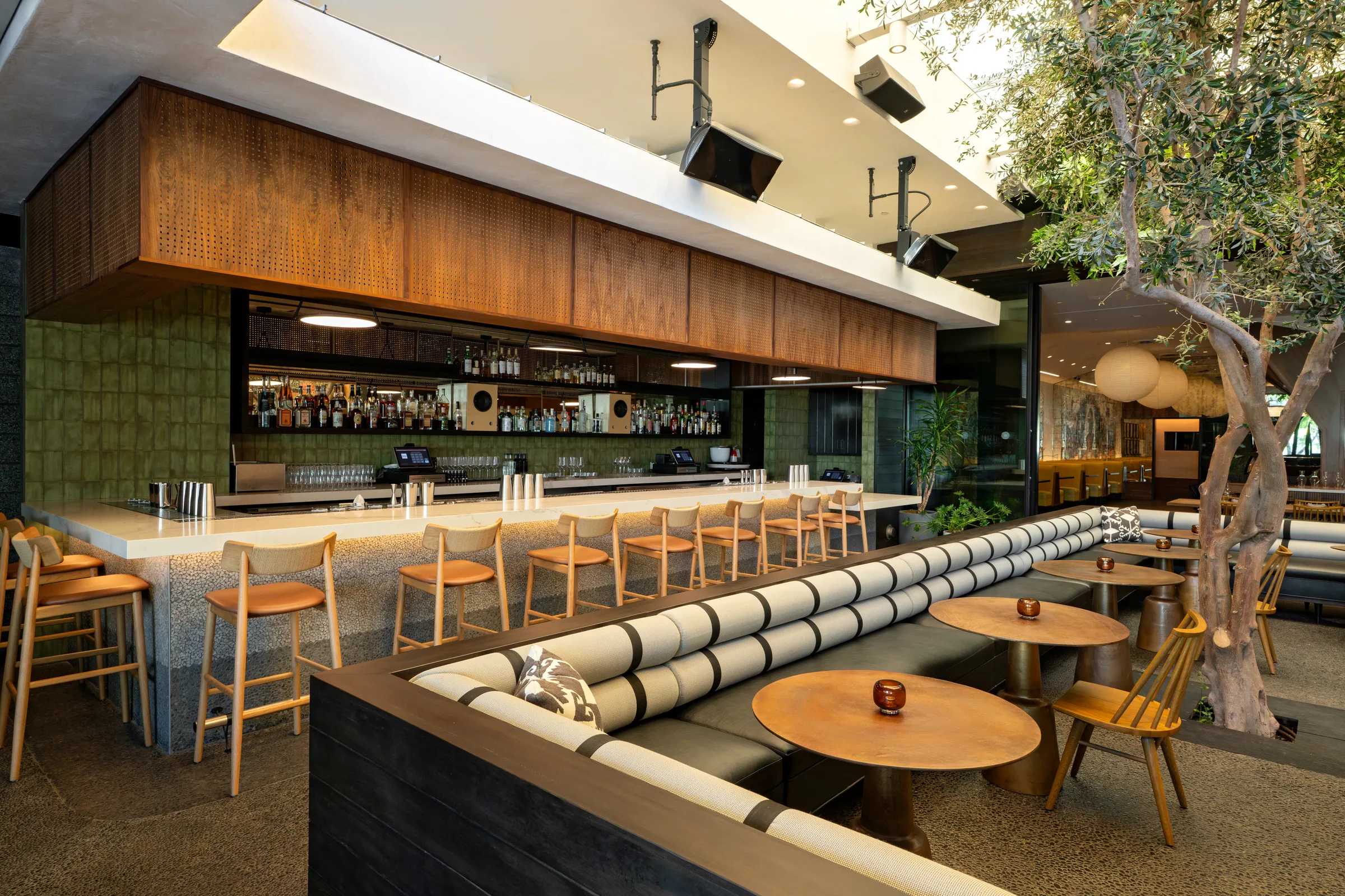 The bar at Darling, walnut canopy over green tile and leather stools