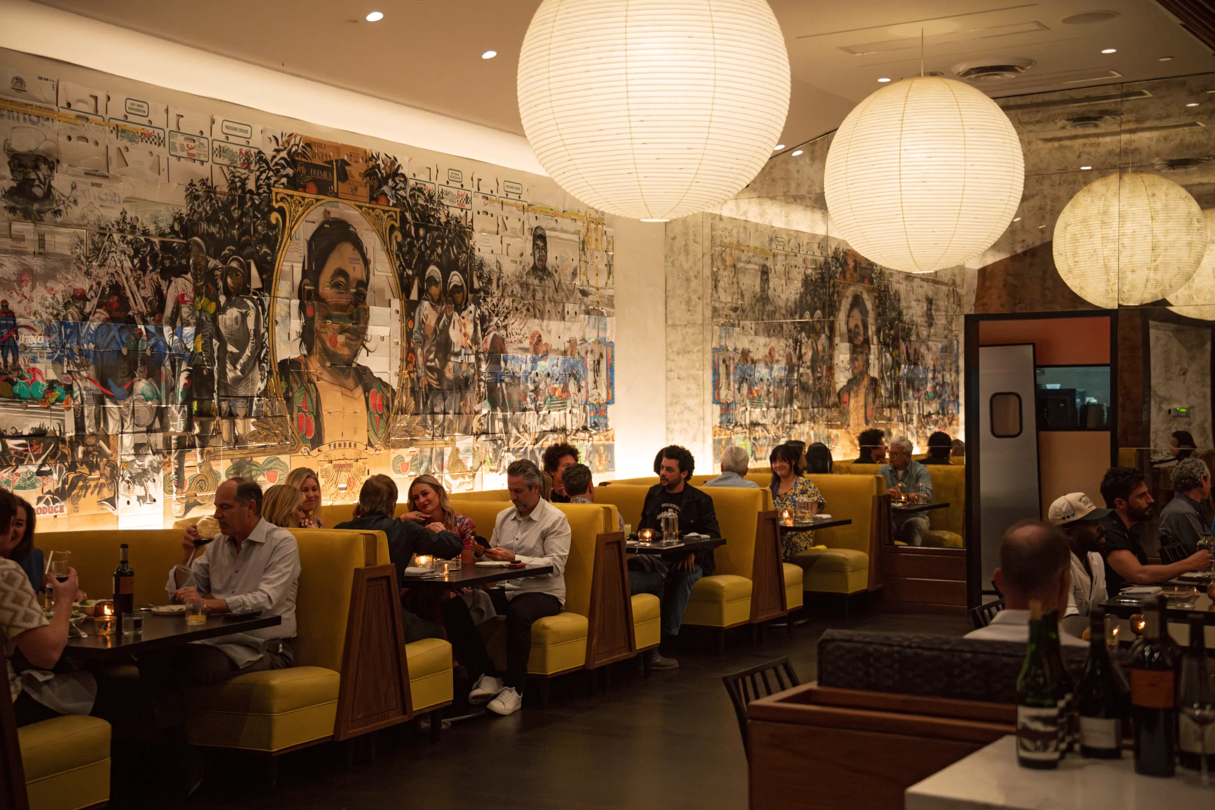 Guests dining in the yellow booths beneath the mural wall at Darling