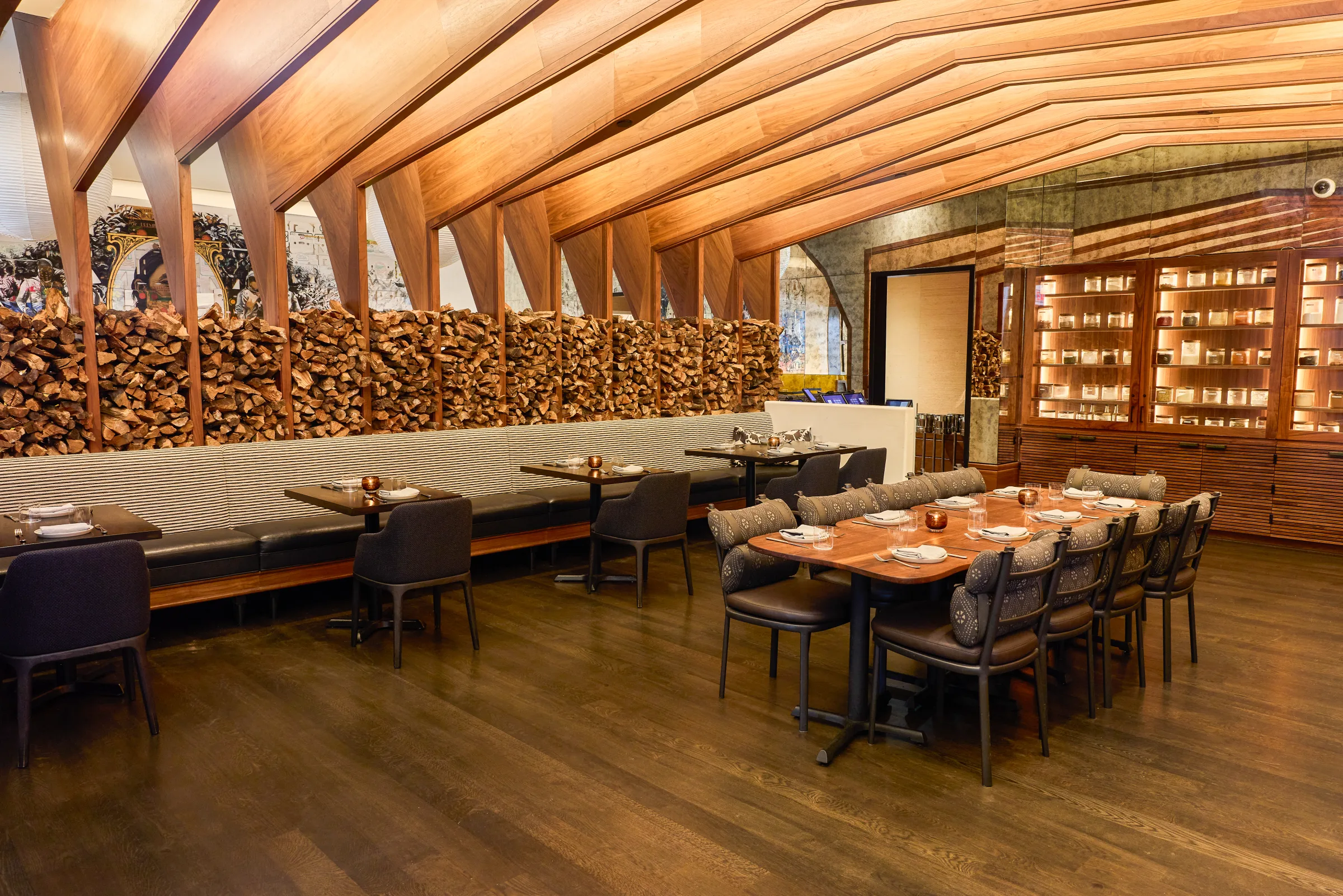 The private dining room at Darling, a long table beneath vaulted timber ribs with a wall of stacked firewood